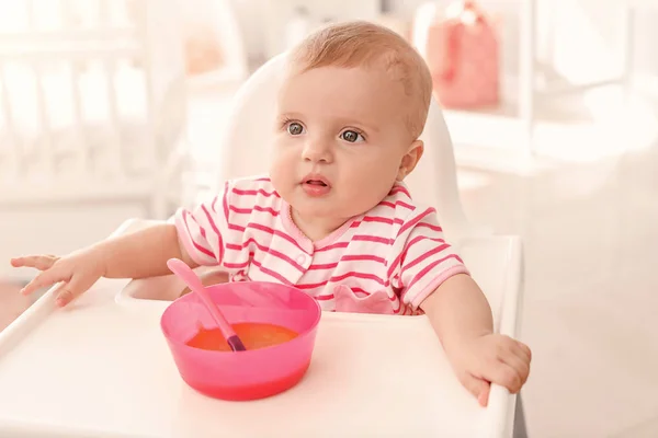 Portrait of cute little baby eating tasty food in kitchen — Stock Photo, Image