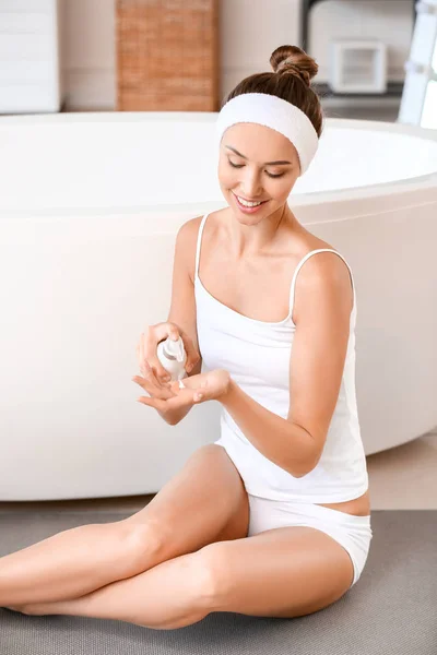 Gyönyörű fiatal nő alkalmazása krém a bőrére a fürdőszobában — Stock Fotó
