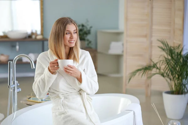 Gyönyörű fiatal nő teát iszik a fürdőszobában — Stock Fotó