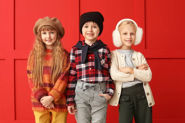 Lindos niños pequeños en ropa de otoño cerca de la pared de color —  Fotos de Stock