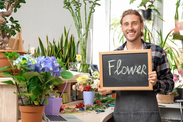 Portrait of male florist holding chalkboard with word FLOWER in shop — Stock Photo, Image