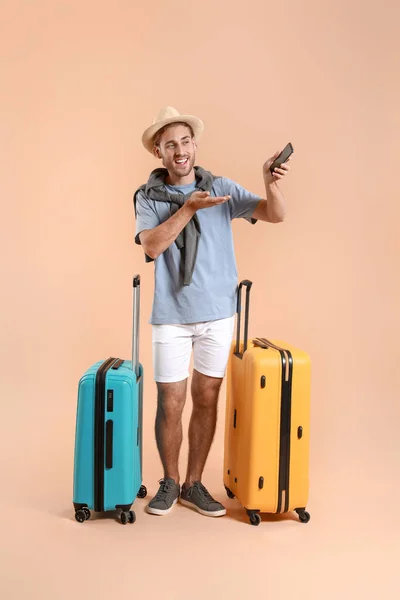 Junger Tourist mit Gepäck auf farbigem Hintergrund — Stockfoto