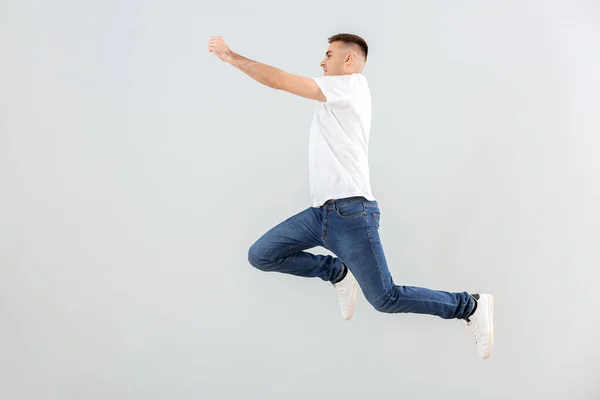 Jumping young man against light background — Stock Photo, Image