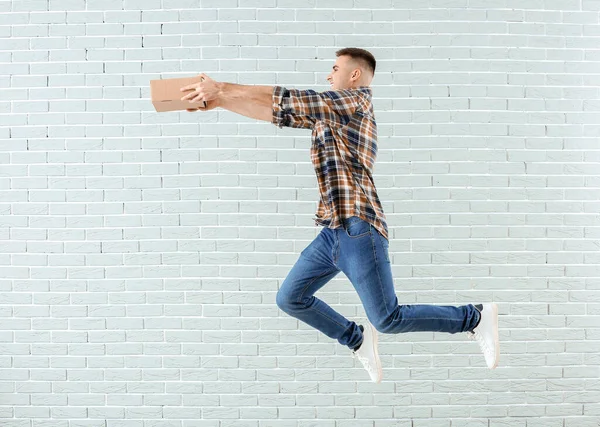 Saltando joven con parcela contra pared de ladrillo —  Fotos de Stock