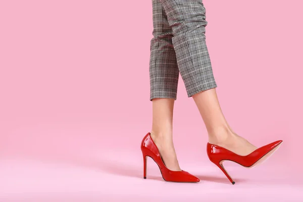 Gambe di giovane donna in scarpe con tacco alto su sfondo di colore — Foto Stock