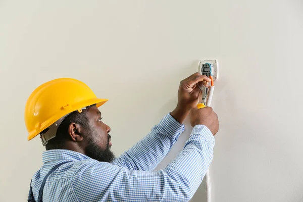 Afroamerikansk elektriker som installerer bryter i rom – stockfoto