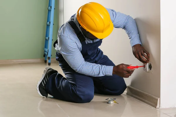 African-American electrician replacing socket in room — Stock Photo, Image