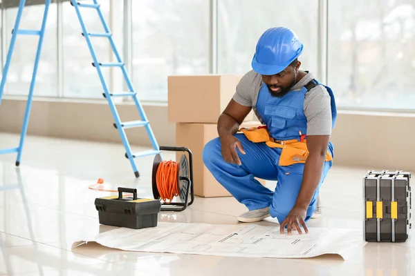 Elettricista afro-americano con schema elettrico in camera — Foto Stock