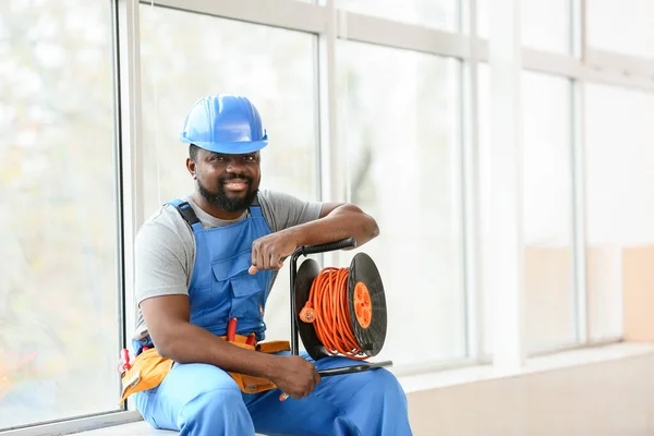 African-American electrician sitting on window sill — Stock Photo, Image