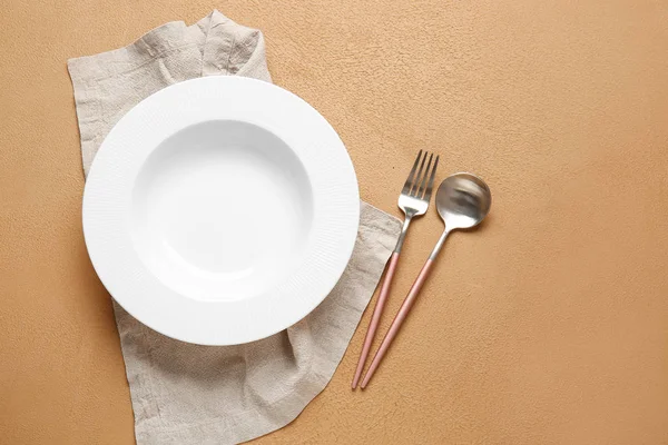 Empty plate, napkin and cutlery on color background — Stock Photo, Image