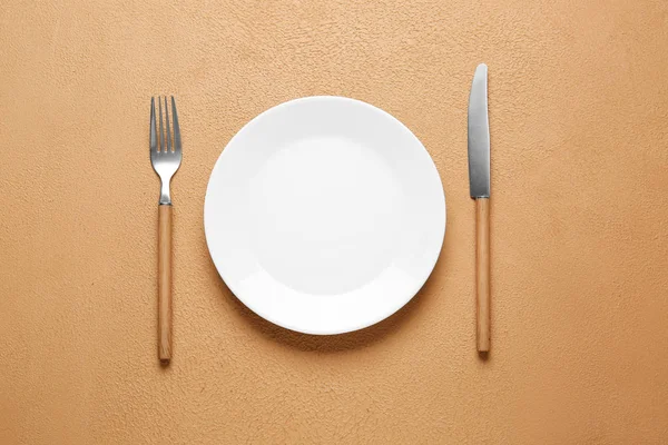 Empty plate and cutlery on color background — Stock Photo, Image