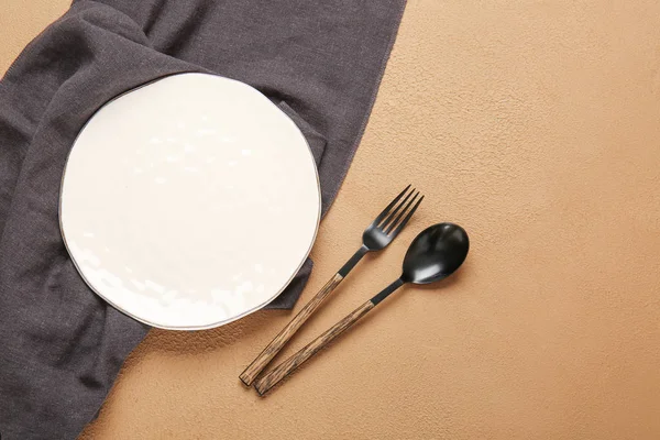 Empty plate, napkin and cutlery on color background — Stock Photo, Image