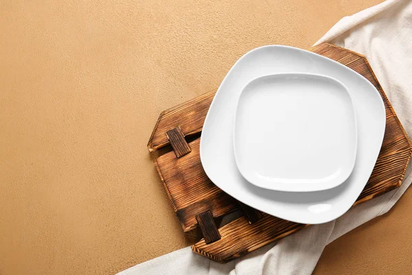 Empty plates, board and napkin on color background — Stock Photo, Image