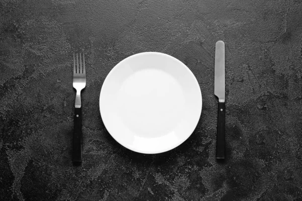 Empty plate and cutlery on dark background — Stock Photo, Image