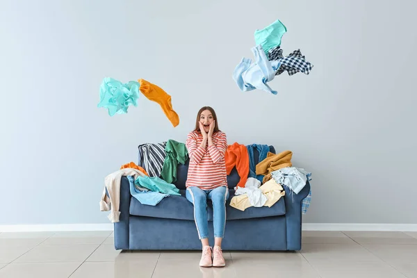Mulher excitada com montão de roupas no sofá dentro de casa — Fotografia de Stock