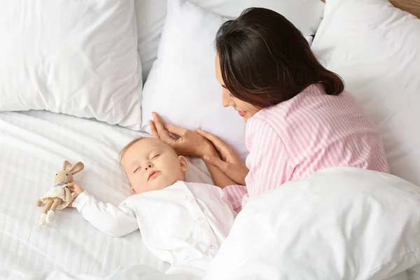 Mladá žena a její spící dítě v posteli — Stock fotografie