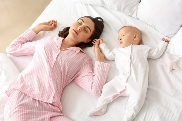 Mladá žena a její dítě spí v posteli — Stock fotografie