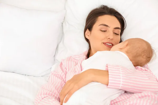 Mujer joven y su bebé durmiendo en la cama —  Fotos de Stock