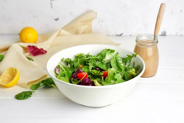 Bowl with vegetable salad and jar of tasty tahini on table — Stock Photo, Image