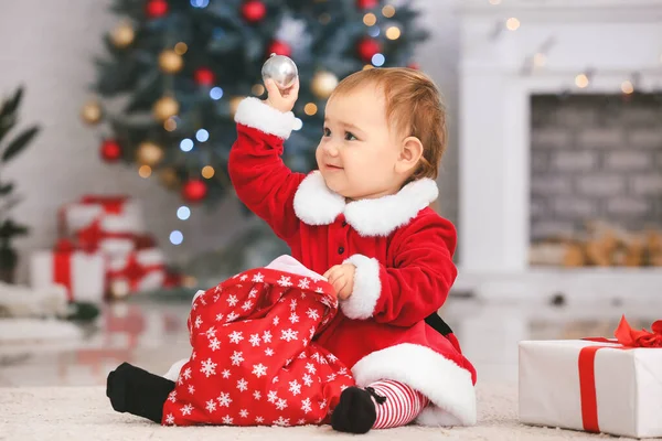 Cute little baby in Santa Claus costume and with Christmas gifts at home — Stock Photo, Image