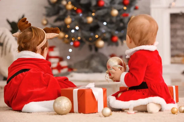 Söta små barn i tomte kostym och med julklappar hemma — Stockfoto