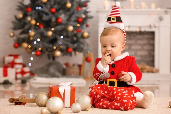 Bebê bonito em traje de Papai Noel e com presente de Natal em casa — Fotografia de Stock