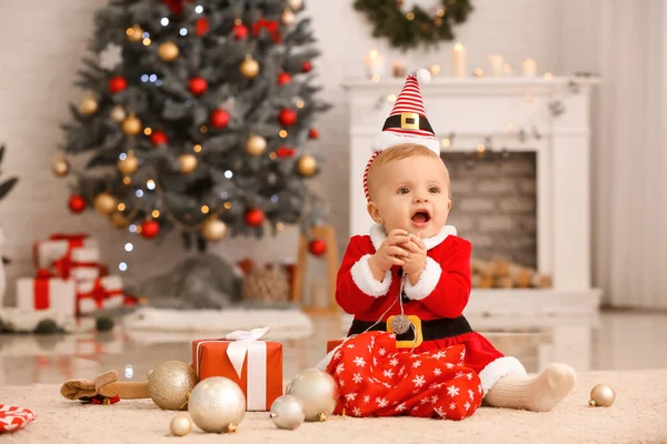 Bebê bonito em traje de Papai Noel e com presentes no quarto decorado para o Natal — Fotografia de Stock