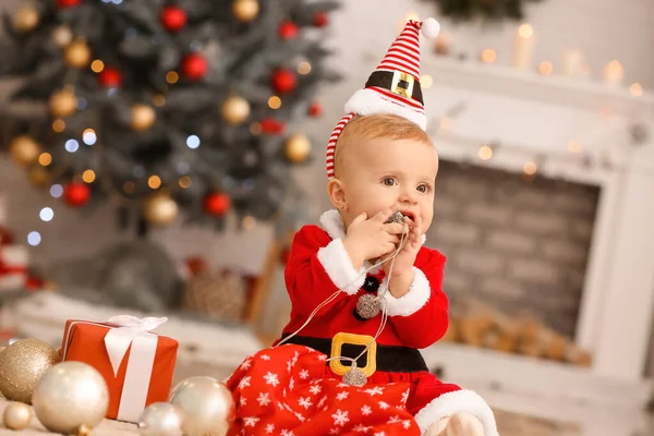 Cute little baby in Santa Claus costume in room decorated for Christmas — Stock Photo, Image