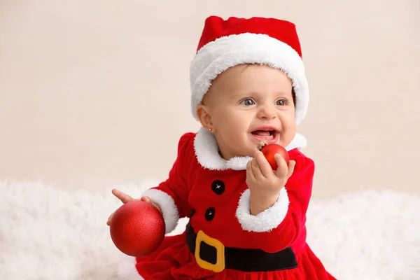 Bebê bonito em traje de Papai Noel e com bolas de Natal em casa — Fotografia de Stock