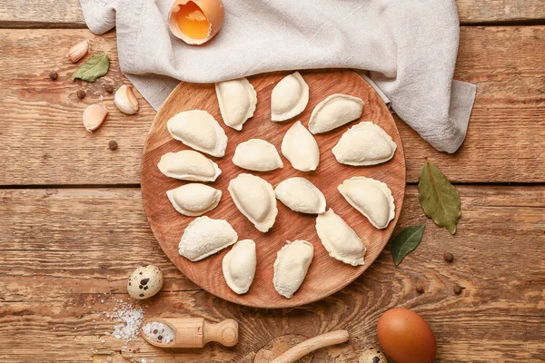 Plate with raw dumplings on wooden background — Stock Photo, Image