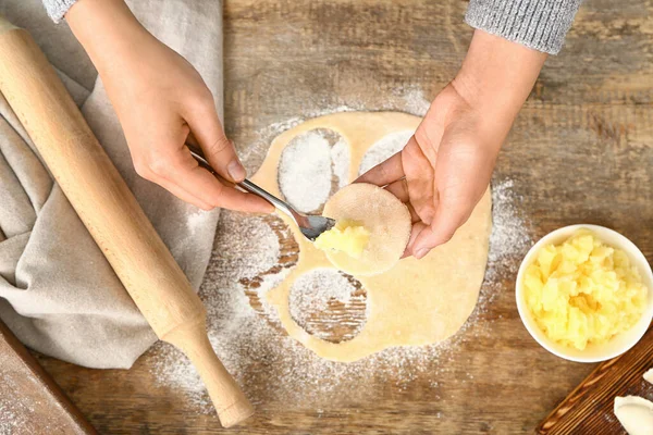 Mujer cocinando sabrosos dumplings en la mesa —  Fotos de Stock