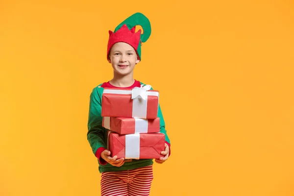 Kleiner Junge im Elfenkostüm und mit Geschenken auf farbigem Hintergrund — Stockfoto