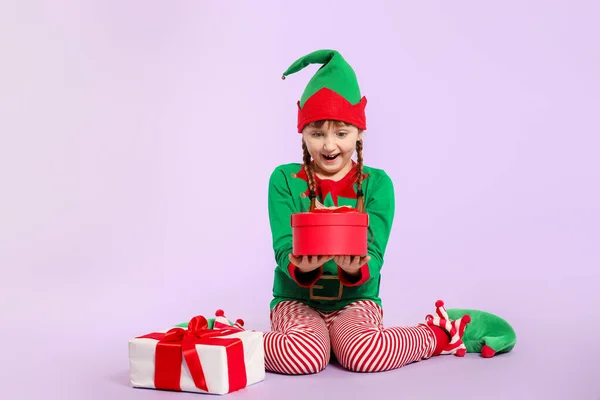 Überraschte Mädchen im Elfenkostüm und mit Geschenken auf farbigem Hintergrund — Stockfoto