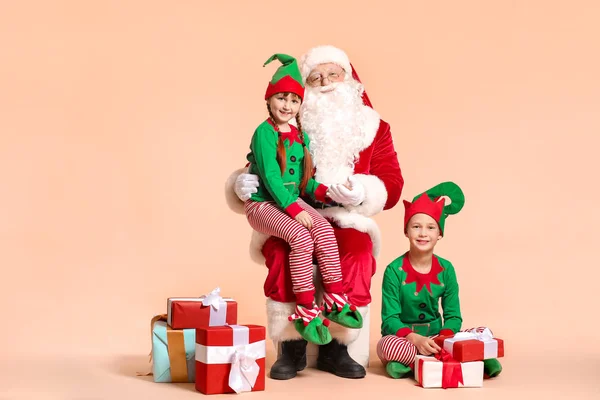 Père Noël et petits enfants elfes avec des cadeaux sur fond de couleur — Photo
