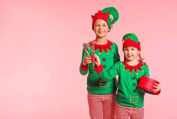 Kleine Kinder im Elfenkostüm, mit Geschenk und Zuckerstangen auf farbigem Hintergrund — Stockfoto