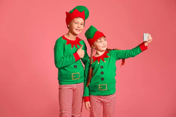 Små barn i kostym nisse tar selfie på färg bakgrund — Stockfoto