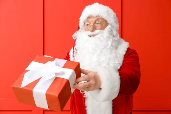Санта-Клаус с подарком на цветном фоне — стоковое фото
