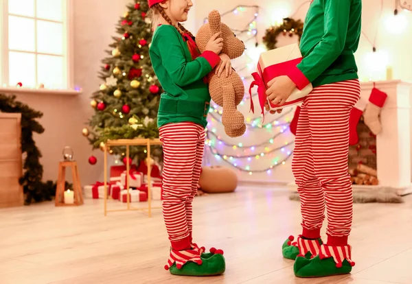 Niños pequeños disfrazados de elfo, regalo con osito de peluche en la habitación decorada para Navidad — Foto de Stock