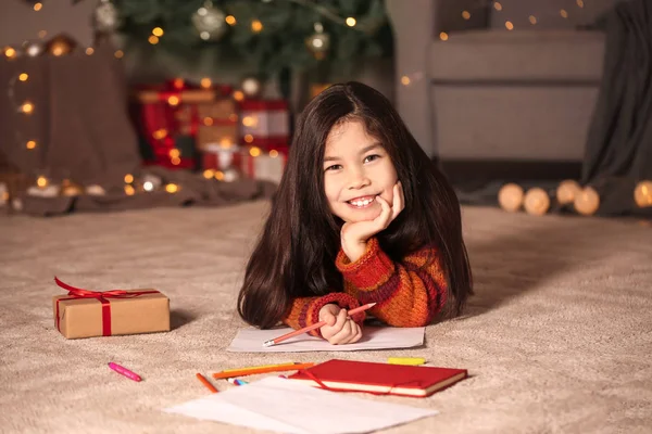 Nettes kleines Mädchen schreibt an Heiligabend Brief an den Weihnachtsmann zu Hause — Stockfoto