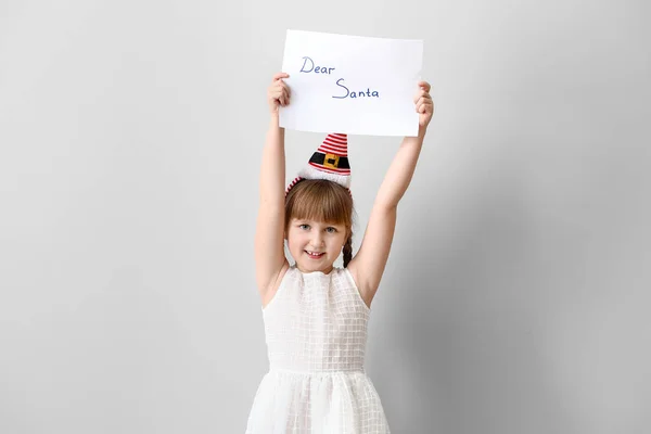 Beyaz arka planda Noel Baba 'ya mektup yazan sevimli küçük bir kız. — Stok fotoğraf