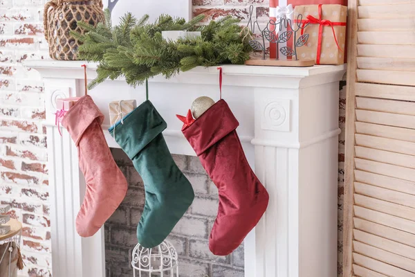 Christmas socks with gifts hanging on fireplace in room — 스톡 사진