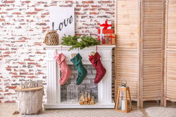Christmas socks with gifts hanging on fireplace in room — Stock Photo, Image