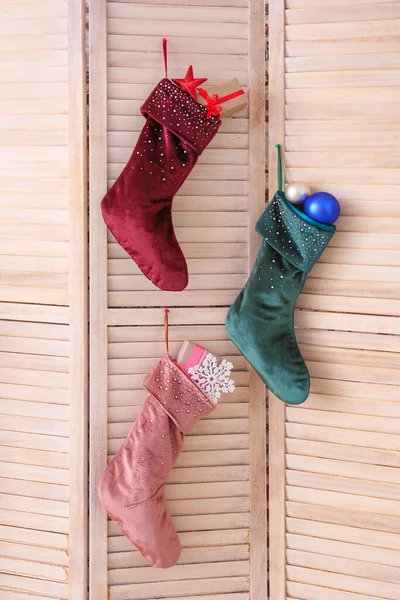 Christmas socks with gifts hanging on folding screen — Stock Photo, Image