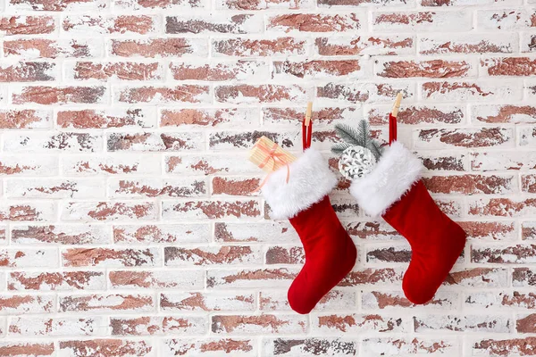 Calcetines de Navidad con regalos colgados en la pared de ladrillo — Foto de Stock