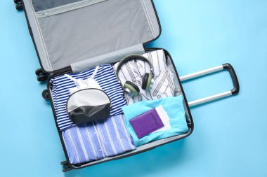 Renkli arka planda paketlenmiş giysiler, pasaport ve aksesuarlar.