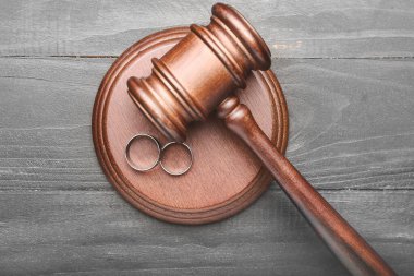 Judge's gavel and rings on wooden background. Concept of divorce clipart