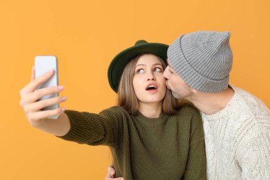 Renkli arka planda selfie çeken genç çift.