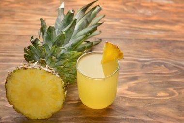 Taze kesilmiş ananas ve ahşap zeminde meyve suyu.