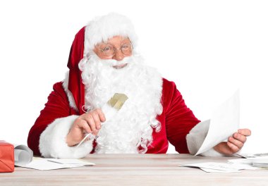 Noel Baba beyaz arka planda hediyelerin listesini yapıyor.