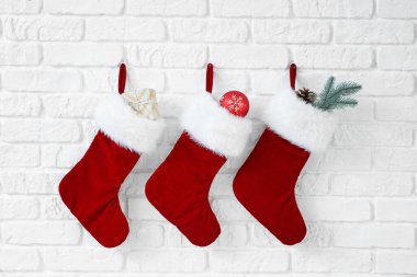 Beyaz duvarda asılı hediyeli Noel çorapları
